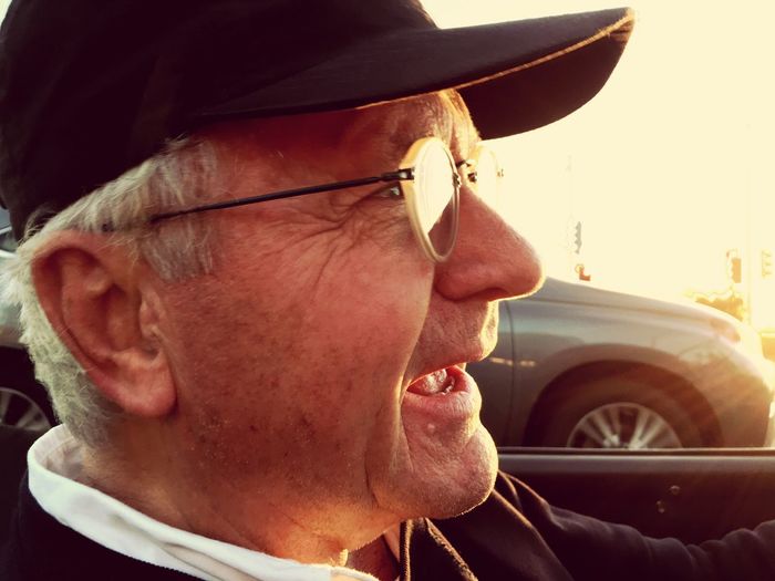 Close-up of smiling senior man wearing cap while sitting in car