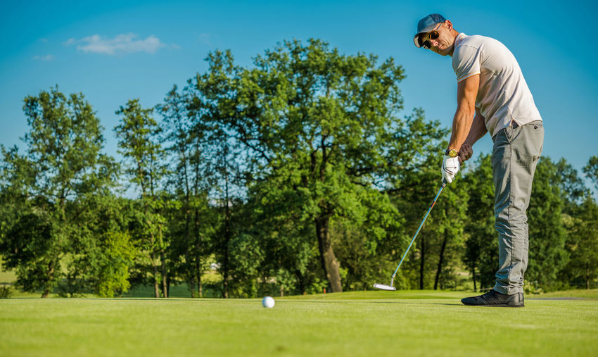 Low angle view of man standing playing golf on field