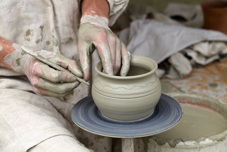 Midsection of potter making clay container at workshop