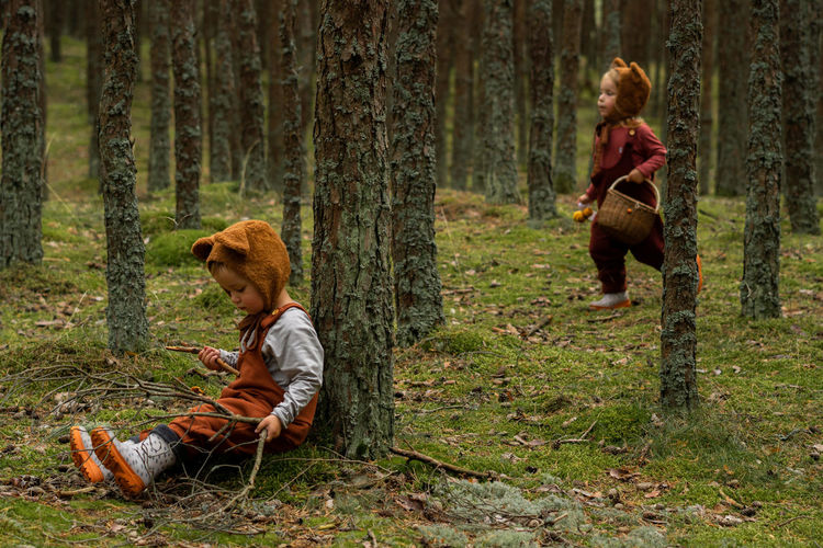 Toddler baby twins in bear bonnets playing and having fun in the woods