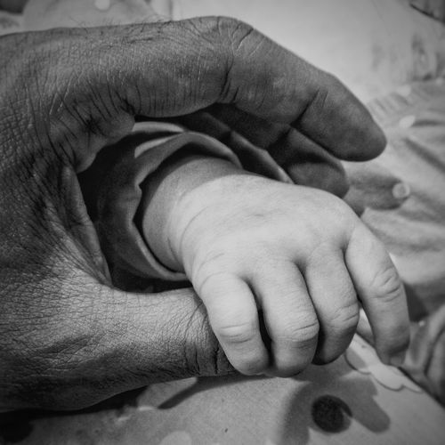 Cropped image of man holding child hand