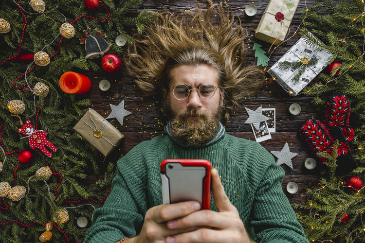 Portrait of man using mobile phone on christmas tree