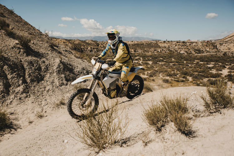 Male biker with protective sportswear riding motorcycle on sunny day