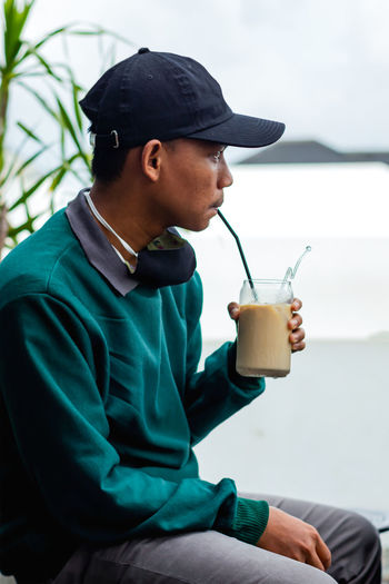 Young man drinking glass sitting on table
