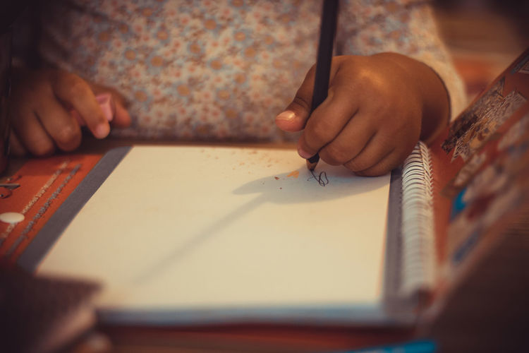 Close-up of left handed child writing on a paper.