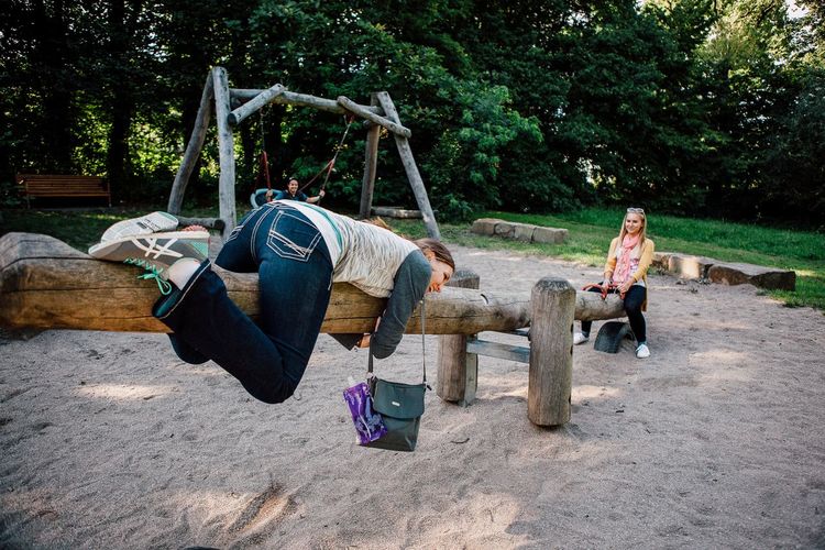 Young female friends playing on wooden seesaw at park