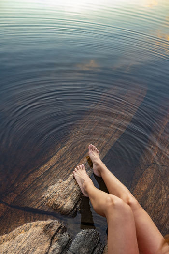 Womans feet on rocks at lake
