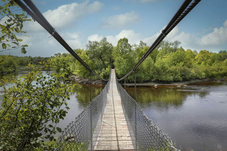 Footbridge over water against sky