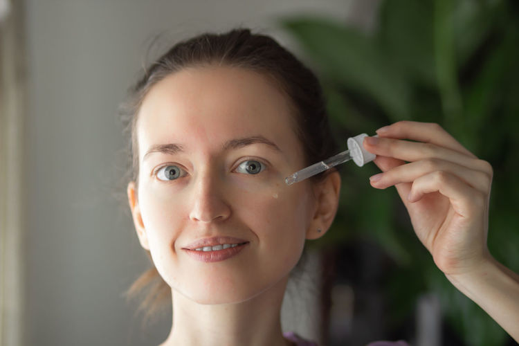 Woman using facial vitamin serum or essential oil with pipette, applying on face. skincare concept