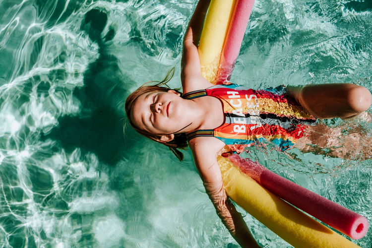 Young girl floating on her back in pool with eyes closed
