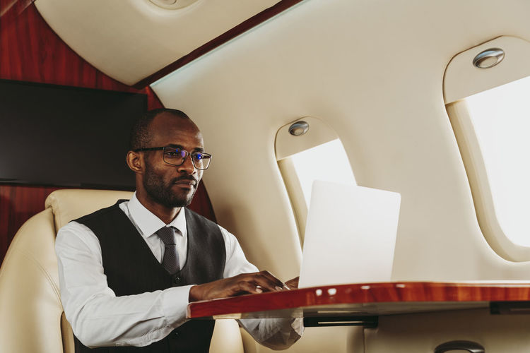 Businessman using laptop while working in private jet