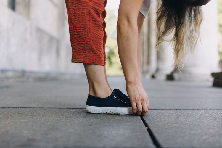 Low section of women standing on street bending forward 