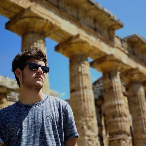 Man wearing sunglasses against old ruins