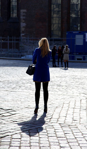 Rear view of woman standing on paved footpath