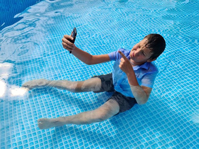 Boy in the pool taking a selfie