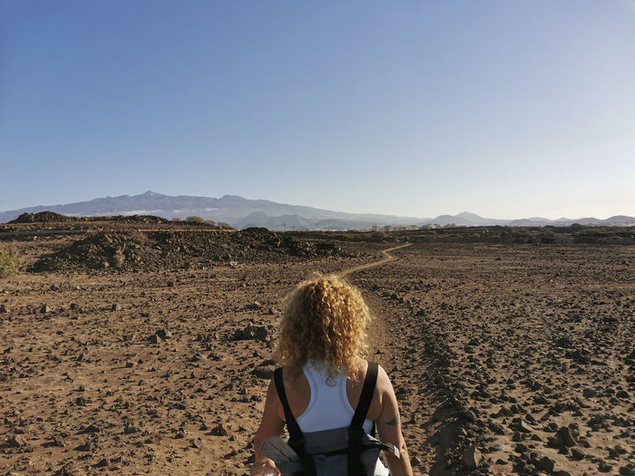 Rear view of woman standing on land against sky