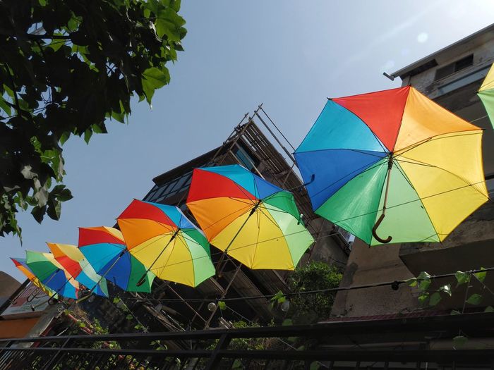 Low angle view of multi colored umbrellas against sky