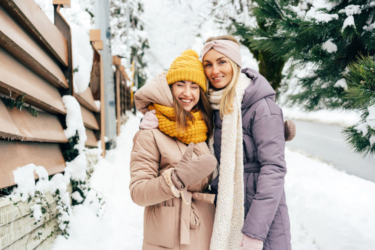 Portrait of smiling young women standing in snow