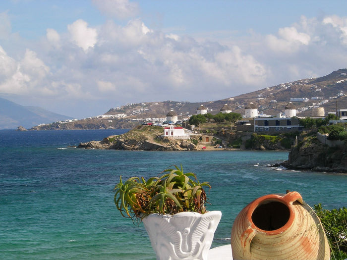 Potted plant and urn against sea and mountains