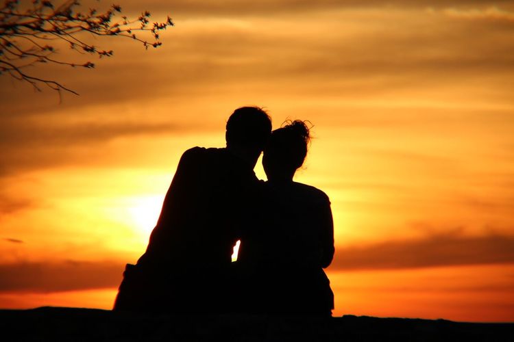 Silhouette couple against orange sky during sunset
