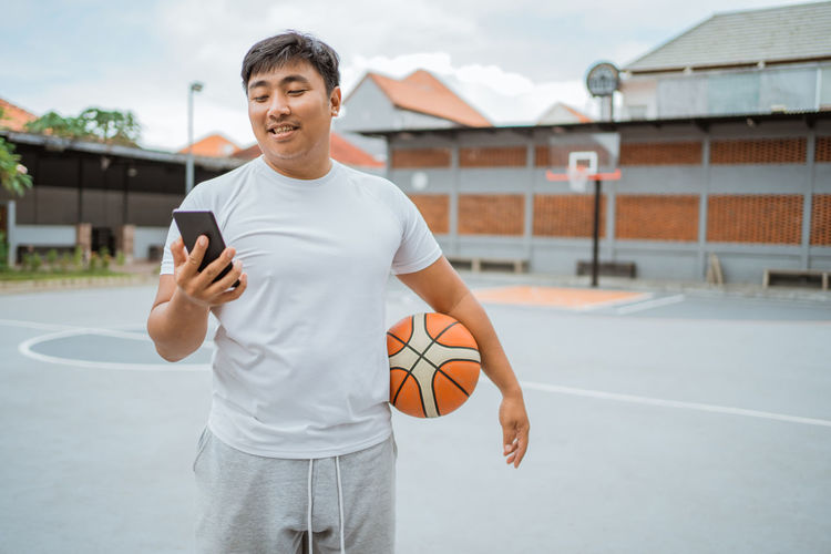 Man using mobile phone on basketball court