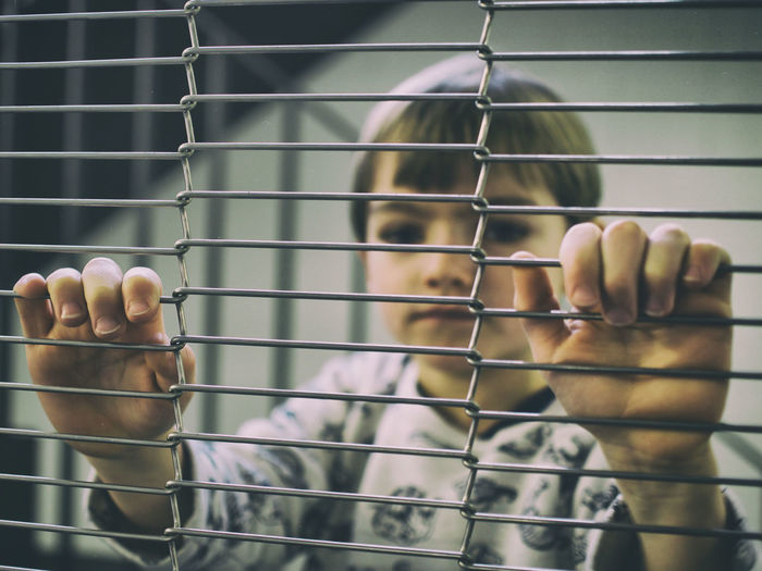 Close-up of boy behind fence