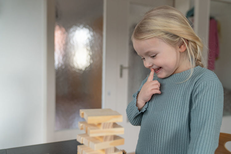Toddler girl looks curiously on a wooden tower