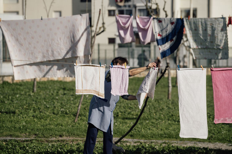 Woman tending clothes outside on a park in a neighbourhood in coastal area espinho , portugal 2023