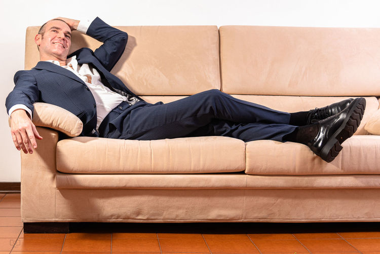 Midsection of man relaxing on sofa
