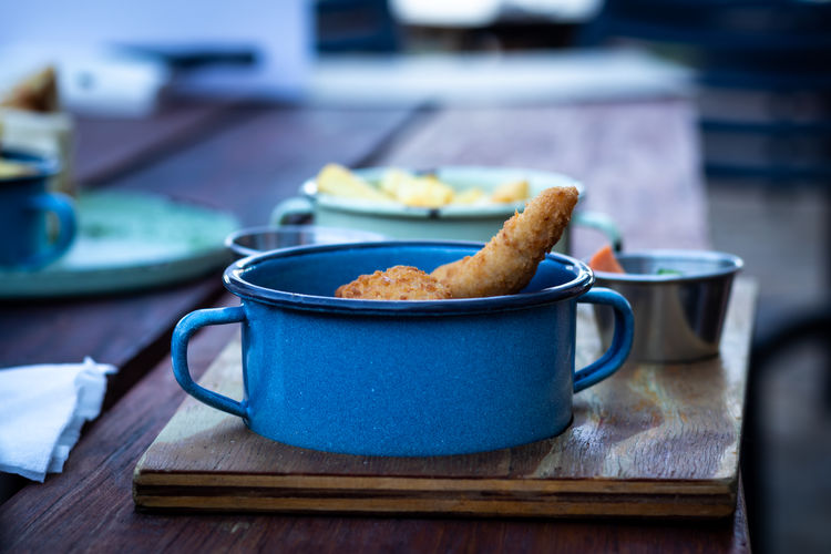 Fried chicken pieces in a blue enamel plate on a wooden table
