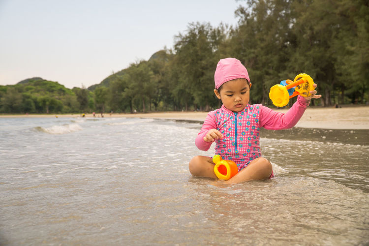 Cute girl playing with toy in water