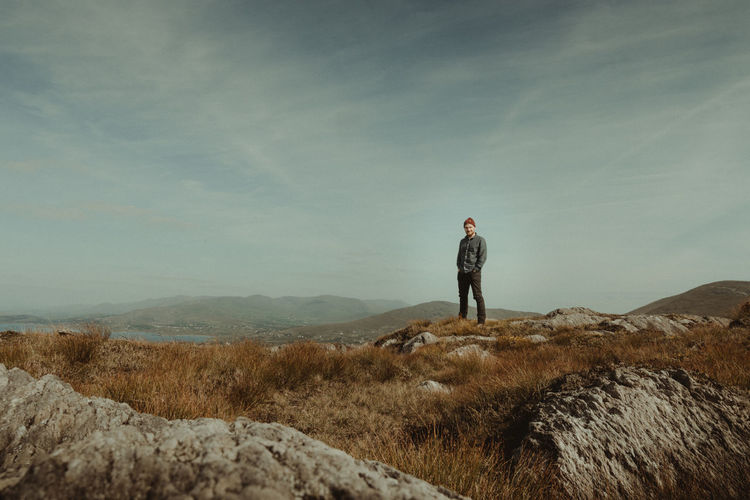 Man standing on rock against sky at ireland