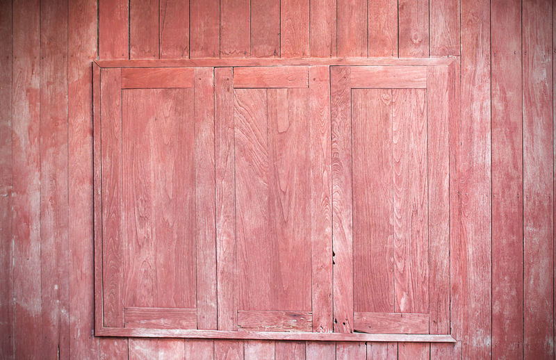 Decorative red window on an old red wood wall
