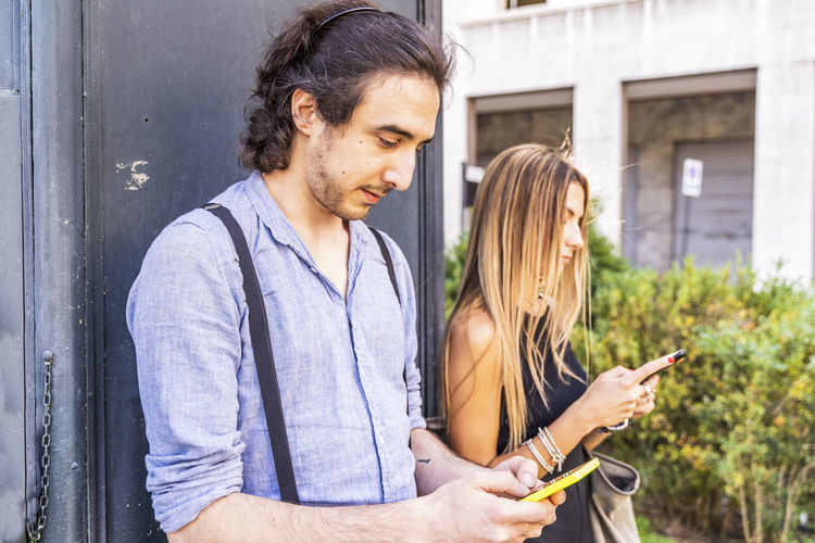 Young couple using smart phone while standing outdoors