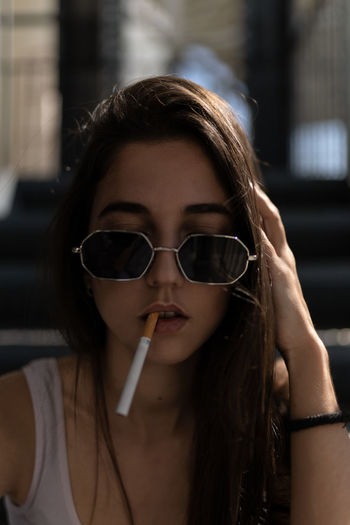 Portrait of young woman holding sunglasses