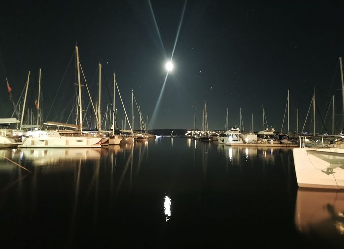 Sailboats moored in marina at night