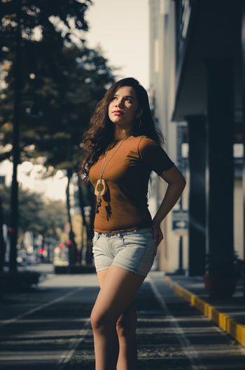 Beautiful young woman standing on street in city