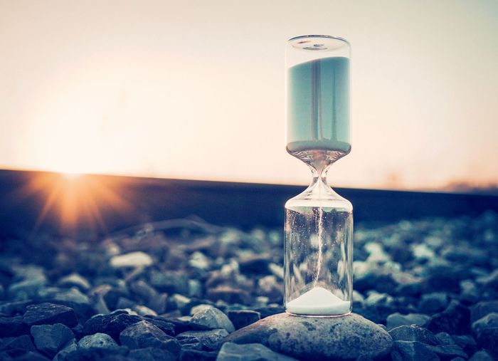 Close-up of hourglass on railroad track during sunset