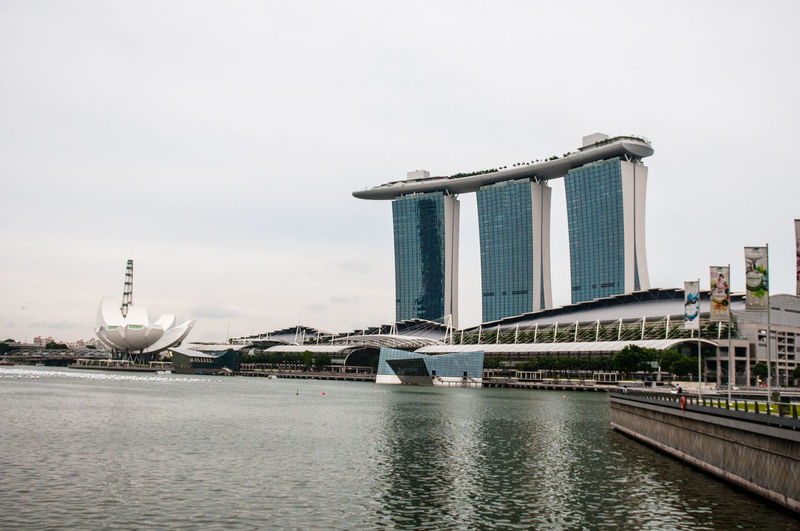 Marina bay sands and artscience museum by sea against sky in city