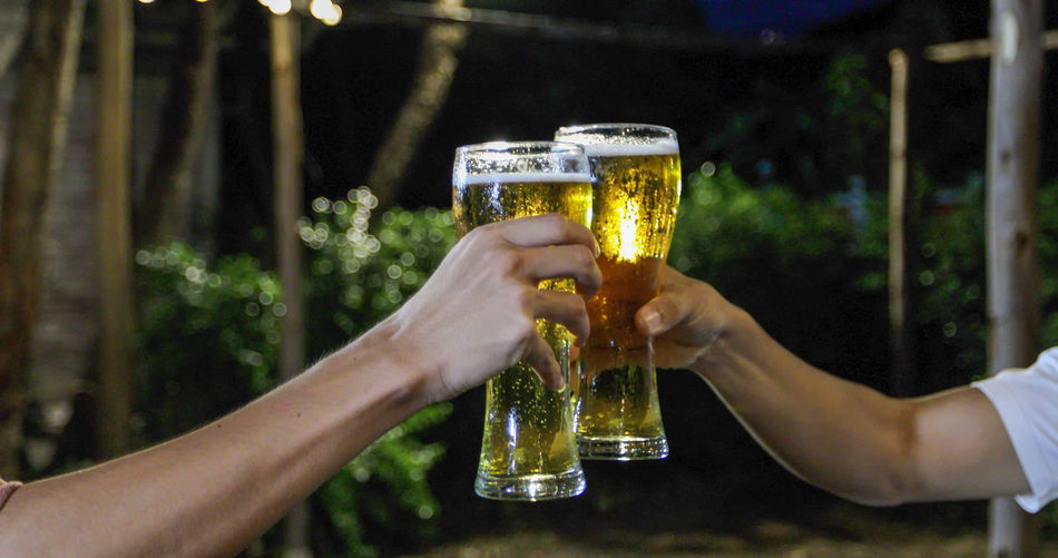 Cropped hands of friends toasting beer glasses