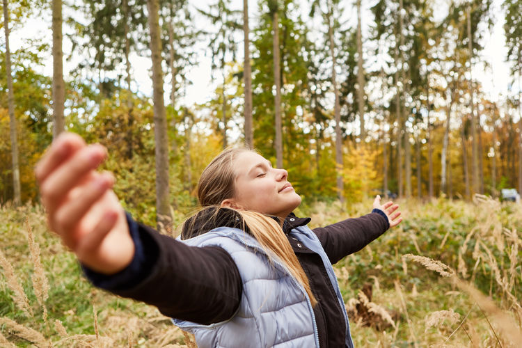 Side view of young woman exercising in forest