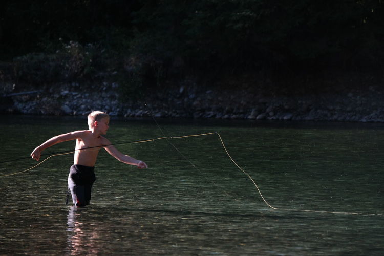 Shirtless boy fishing in lake