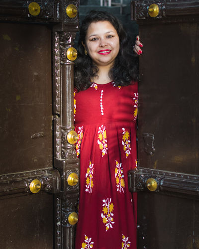 Portrait of smiling woman standing against door