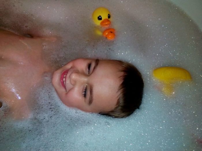 High angle view of shirtless smiling boy in bathtub