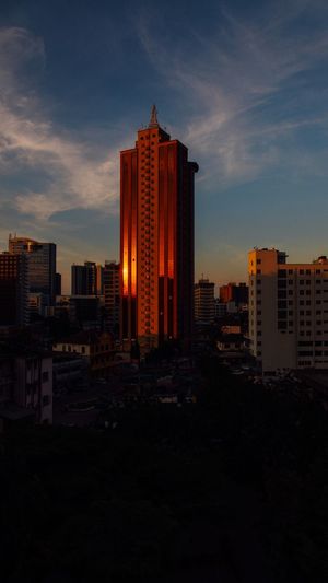 Modern buildings in city against sky at sunset