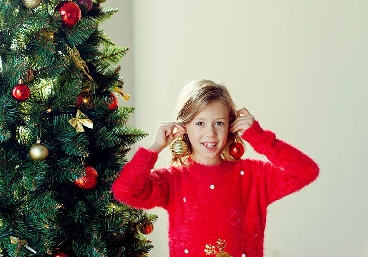 Portrait of smiling girl decorating christmas tree at home
