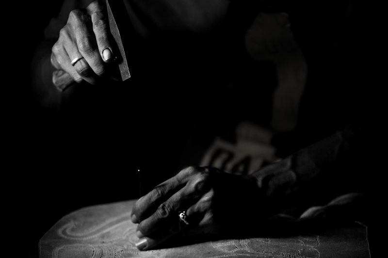 Cropped hands of person carving on stone with tools in darkroom