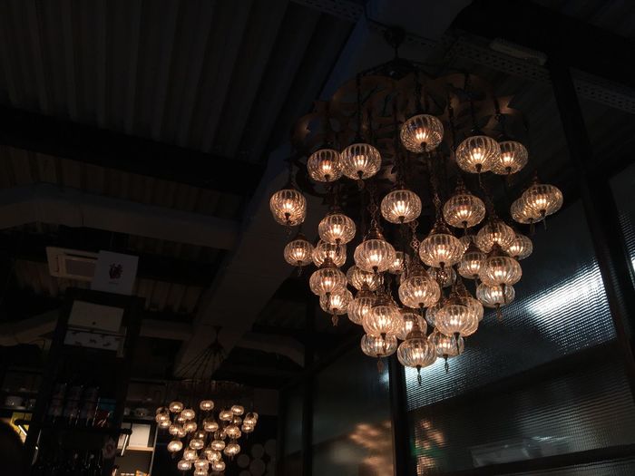 Low angle view of illuminated chandelier hanging on ceiling