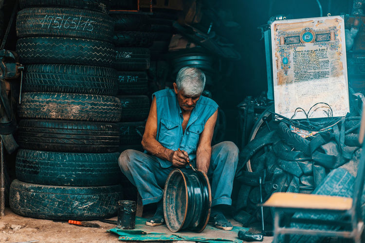 Man working while sitting at garage