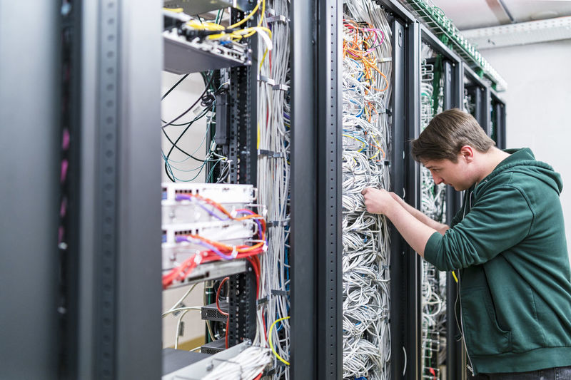 Teenager working with cables in server room